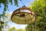 A canvas covered hemisphere with skeletal wooden frame suspended overhead in the tree canopy